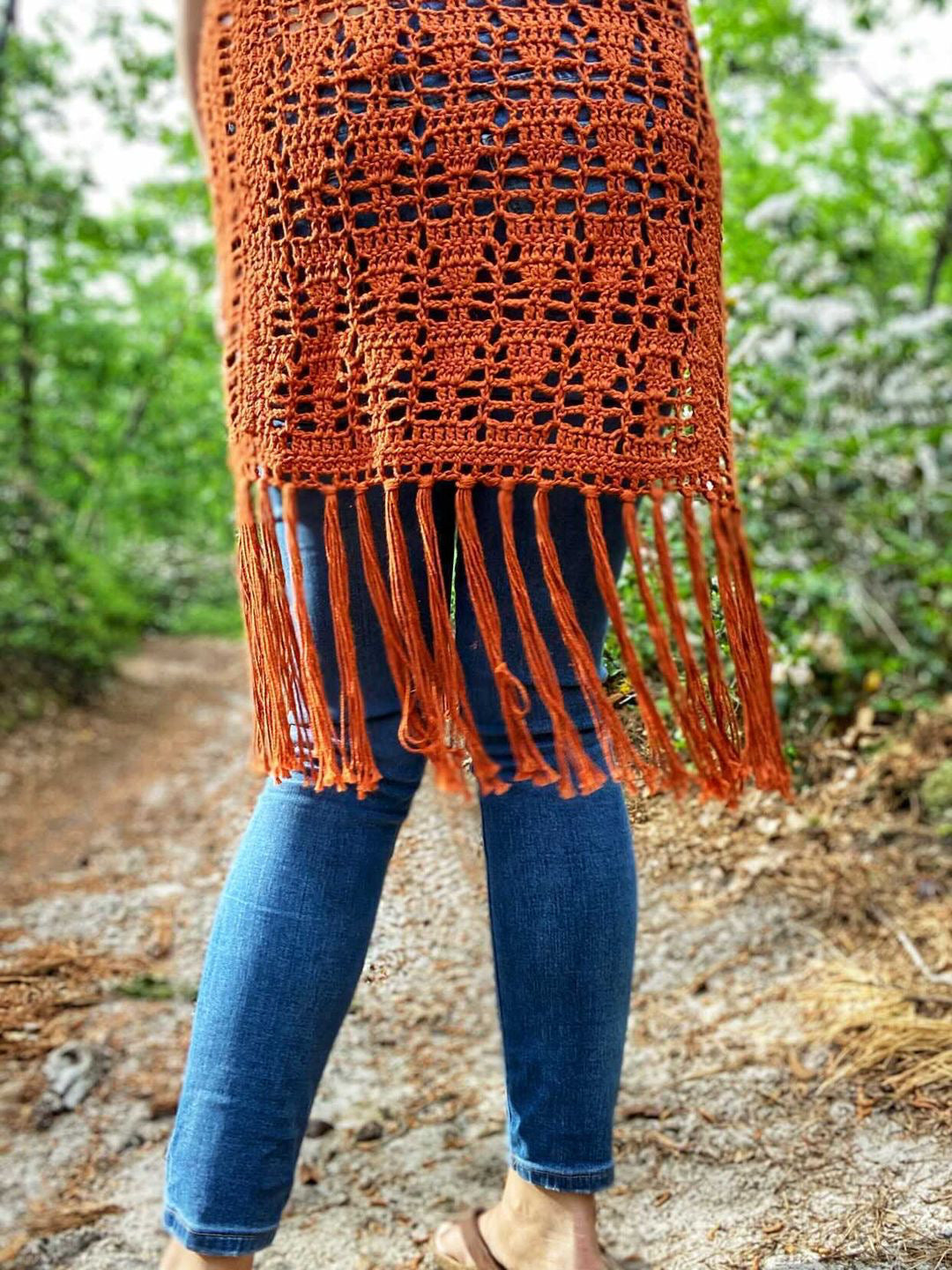 Person wearing an orange crochet fringe shawl outdoors