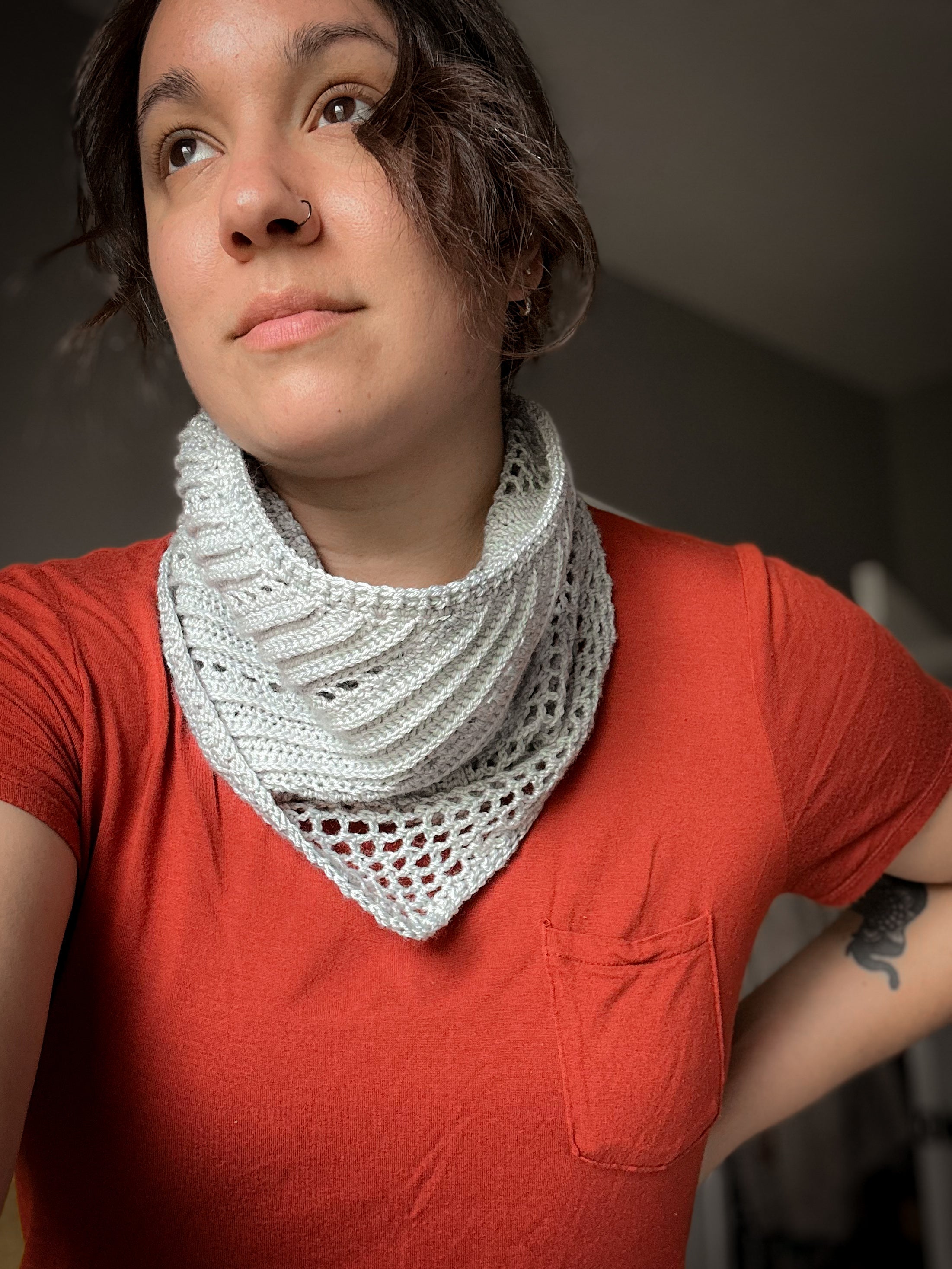 Person wearing a red shirt and a white knitted scarf against a dark background