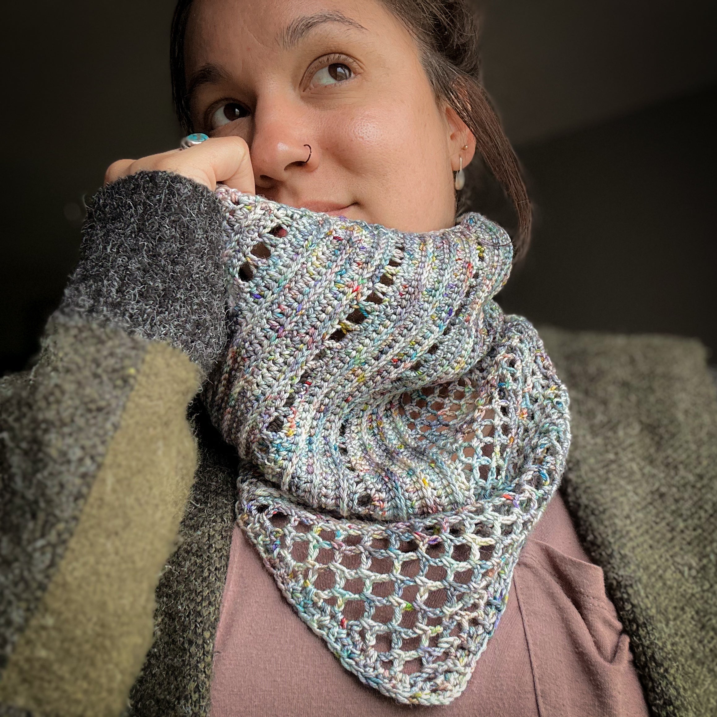 Woman wearing a colorful knitted scarf with a dark background